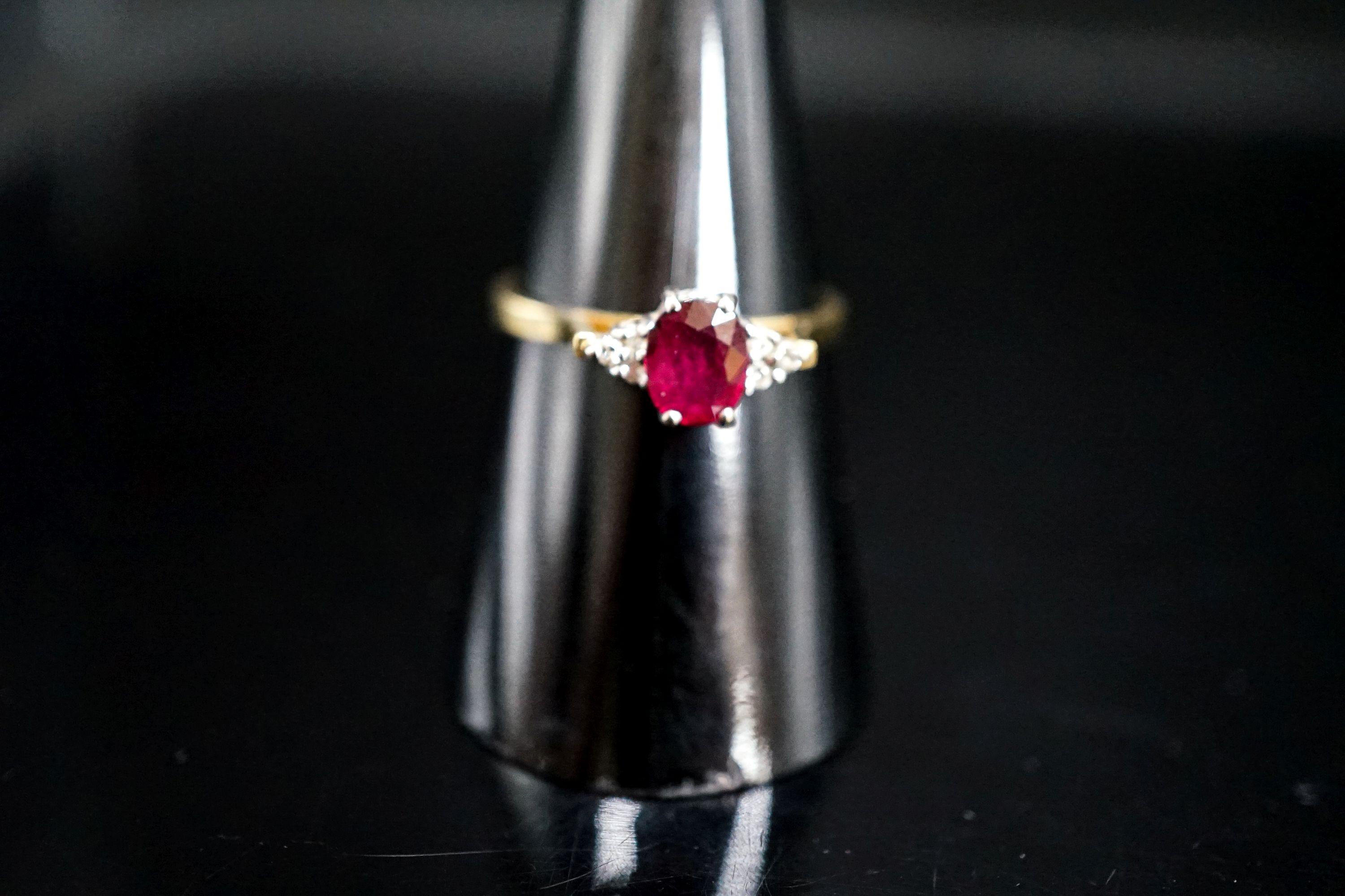 A 750 yellow metal, single stone oval cut ruby and six stone diamond chip set ring, size O, gross weight 2.7 rams.